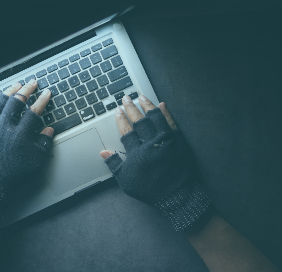 A mans hands in gloves typing on a keyboard