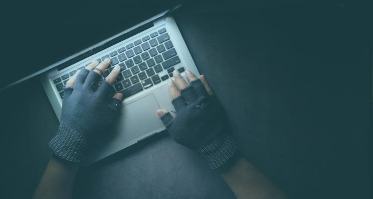 A mans hands in gloves typing on a keyboard